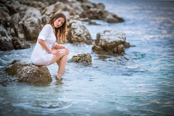 Atraente, jovem mulher relaxante na praia ao pôr do sol — Fotografia de Stock