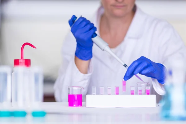 Händerna på en kvinnlig forskare som bedriver forskning i en chemistr — Stockfoto