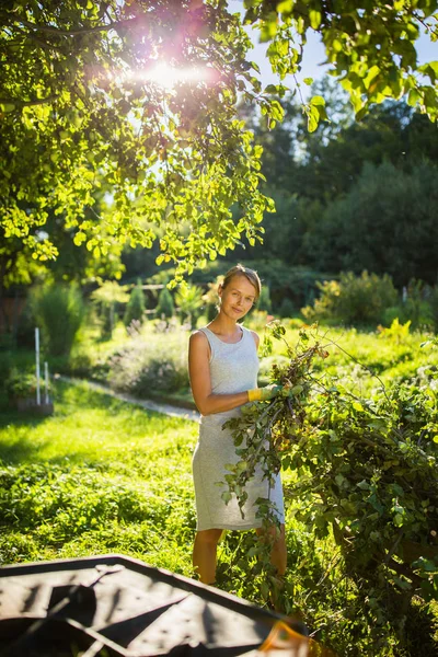 Bonita, joven jardinería en su jardín, cortar ramas — Foto de Stock