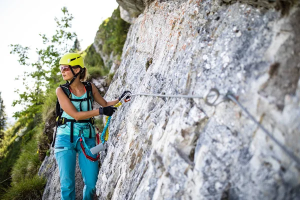 Bastante, escaladora femenina en una vía ferrata escalada en una roca en —  Fotos de Stock