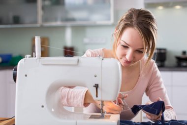 Güzel genç kadın dikiş elbise dikiş makinesi ile 