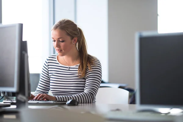 Estudiante guapa y femenina mirando una pantalla de computadora de escritorio —  Fotos de Stock