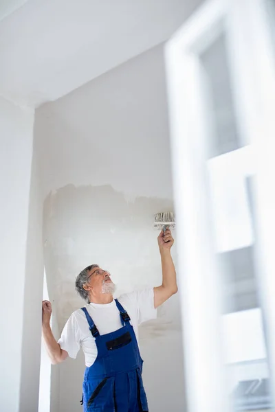 Uomo anziano pittore al lavoro con un secchio di vernice — Foto Stock