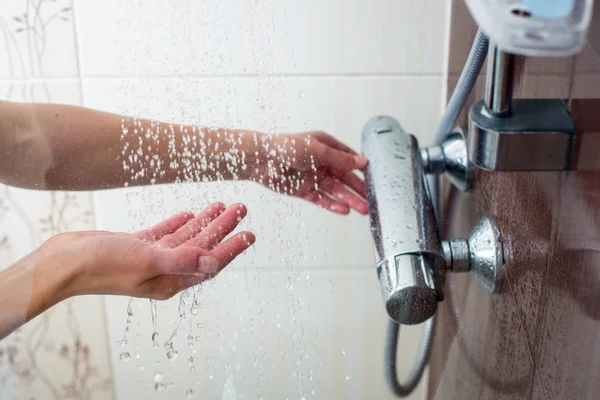 Hands of a young woman taking a hot shower at home — Stockfoto