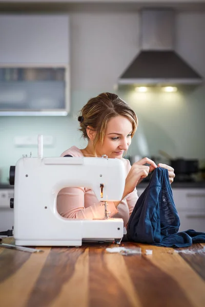 Bella giovane donna che cuce vestiti con macchina da cucire — Foto Stock