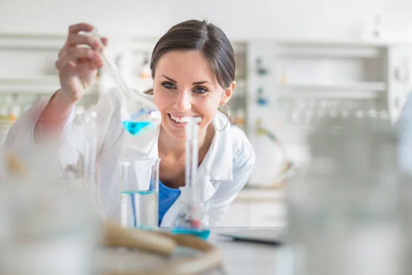 Bir laboratuvarda deneyler yürüten genç, kadın araştırmacı — Stok fotoğraf