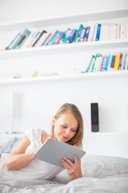 Tablet bilgisayarını kullanarak yatakta, güzel genç bayan