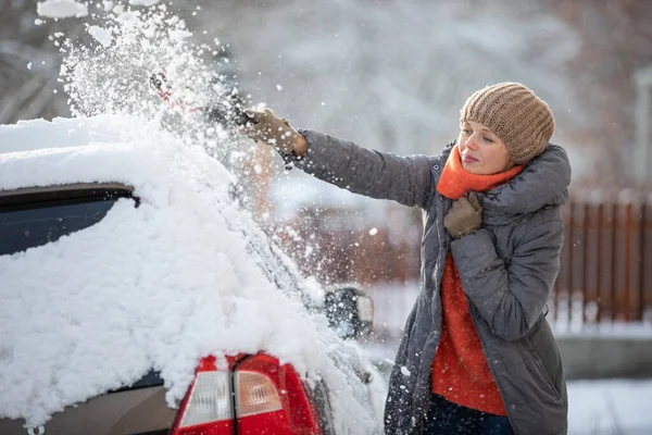 Söt, ung kvinna städa sin bil från snö efter tung snö — Stockfoto