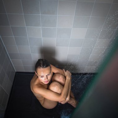 Güzel, genç bir kadın uzun sıcak bir duş alıyor.