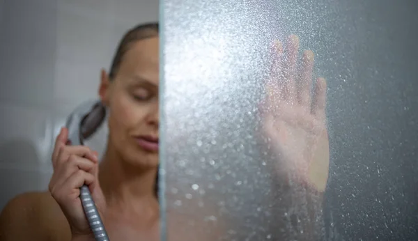 Hübsche, junge Frau unter einer langen heißen Dusche, die ihr Haar wäscht — Stockfoto
