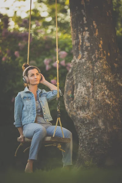 Hezká, mladá žena s sluchátky venku, v krásném parku — Stock fotografie