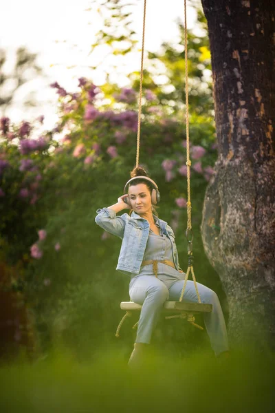 Hezká, mladá žena s sluchátky venku, v krásném parku — Stock fotografie