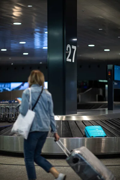 Pessoas em um aeroporto internacional, na zona de reclamação de bagagem — Fotografia de Stock