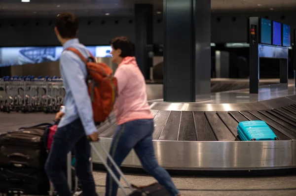 Pessoas em um aeroporto internacional, na zona de reclamação de bagagem — Fotografia de Stock