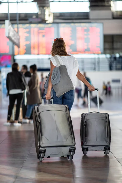 Молодая женщина с багажом в международном аэропорту — стоковое фото