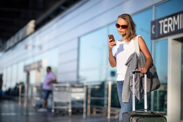 Junge Frau mit ihrem Gepäck auf einem internationalen Flughafen — Stockfoto