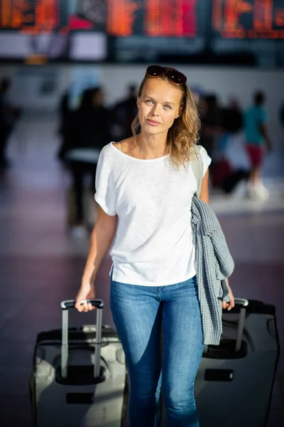 Junge Frau mit ihrem Gepäck auf einem internationalen Flughafen — Stockfoto