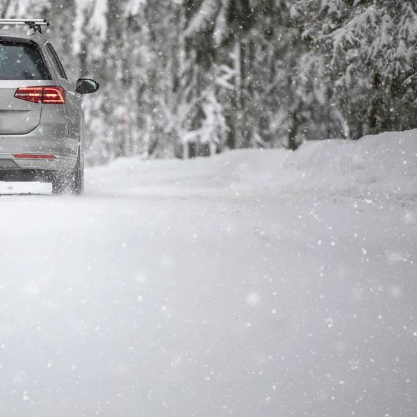 Carro em uma estrada de inverno nevado em meio a florestas — Fotografia de Stock