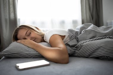 Güzel, genç bir kadın yatağında uyuyor. 