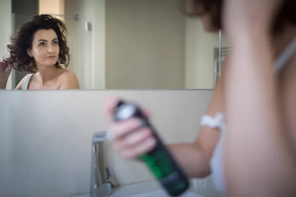 Güzel genç bir kadın saçını banyoda şekillendiriyor. — Stok fotoğraf