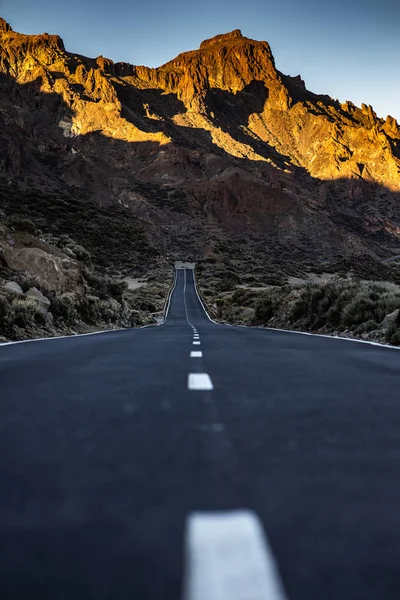 Long road in a mountain valley with a car on it — Stockfoto