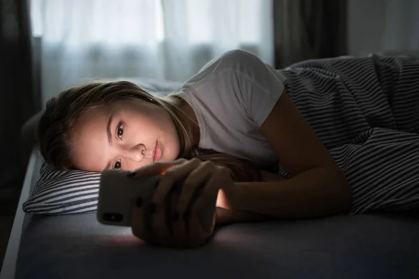 Pretty, young woman sleeping in her bed with her cell phone — Stockfoto