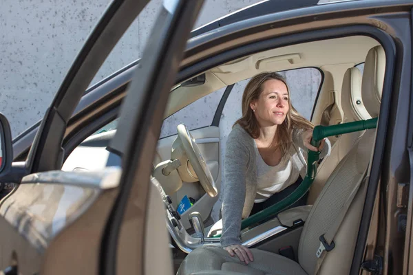 Pretty, middle aged woman vacuum cleaning the interior — Stockfoto