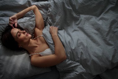 Yatağında uyuyan güzel, genç bir kadın.