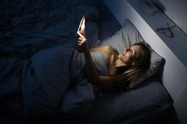Όμορφη, μεσήλικη γυναίκα που χρησιμοποιεί το κινητό της στο κρεβάτι — Φωτογραφία Αρχείου