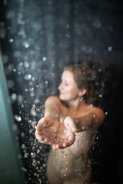 Mujer bonita y joven tomando una larga ducha caliente en un baño moderno — Foto de Stock