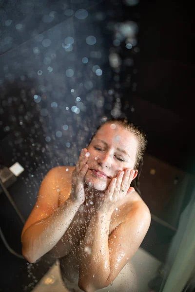 Mujer bonita y joven tomando una larga ducha caliente en un baño moderno —  Fotos de Stock