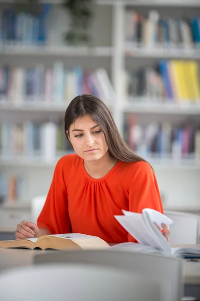 Hübsche, junge Studentin auf der Suche nach einem Buch in der Bibliothek — Stockfoto