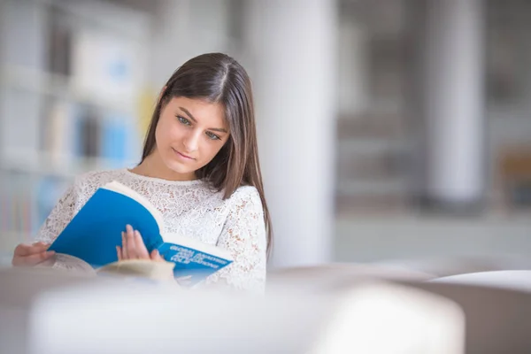 Bonito, jovem estudante universitário à procura de um livro na biblioteca — Fotografia de Stock