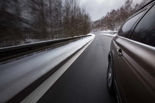 Snelle rijdende auto op een winter alpine besneeuwde weg — Stockfoto