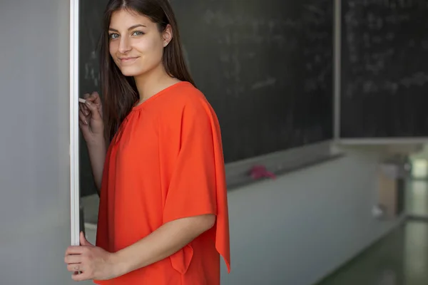 Pretty, young college student/young teacher writing on the chalkboard — Stock Photo, Image