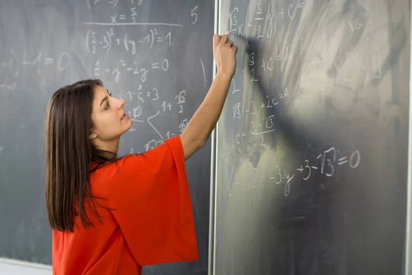 Jolie, jeune étudiante / jeune enseignante écrivant sur le tableau — Photo