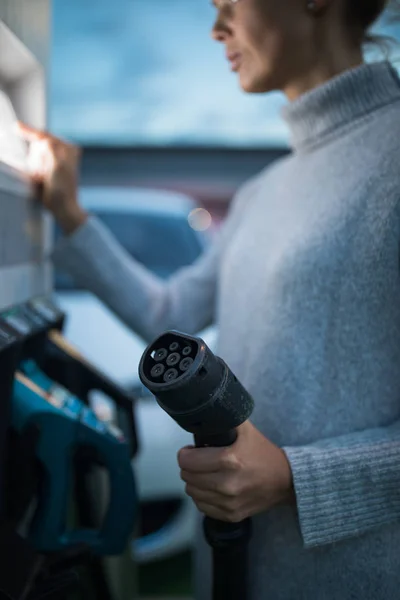 Junge Frau lädt ein Elektrofahrzeug — Stockfoto