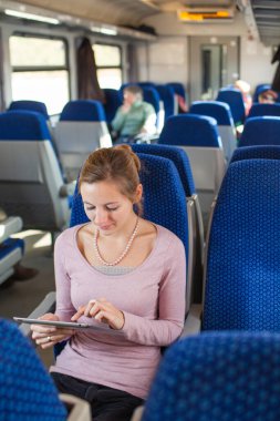 Young woman using her tablet computer while traveling by train clipart