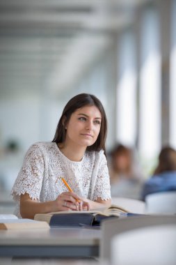 Güzel, genç üniversite öğrencisi kütüphanede bir kitap arıyorum,