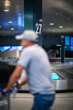 Uluslararası bir havaalanında bavuluyla genç bir kadın, uçuş öncesi kontrol ve güvenlik kontrolünden geçmeden önce