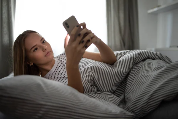 Söt Ung Kvinna Sover Sin Säng Med Sin Mobiltelefon Nära — Stockfoto