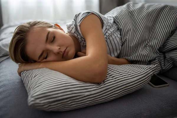 Söt Ung Kvinna Sover Sin Säng Med Sin Mobiltelefon Nära — Stockfoto