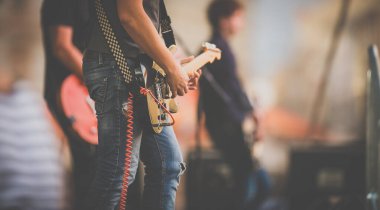 Grup büyük bir kalabalığın önünde, bir sahnede canlı performans