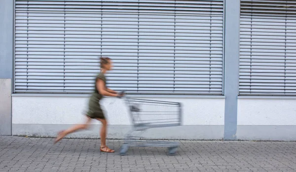 トロリーで食料品の買い物に行く若い女性 — ストック写真