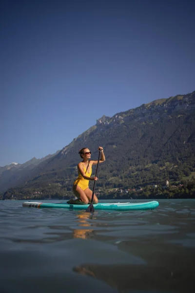 湖の上のパドルボードに乗って美しい夏の日を楽しんでいる若い女性 — ストック写真