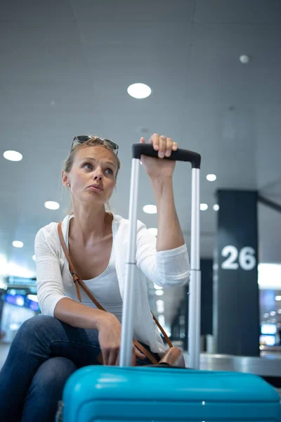 Young woman with her luggage at an international airport, before going through the check-in and the security check before her flight