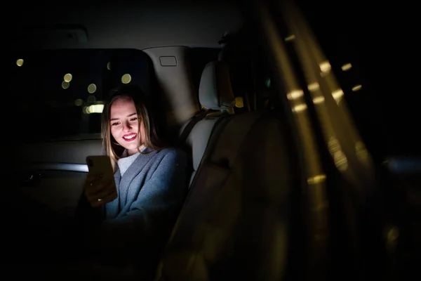 Νεαρή Γυναίκα Κινητό Της Κάθεται Στο Πίσω Κάθισμα Ενός Αυτοκινήτου — Φωτογραφία Αρχείου