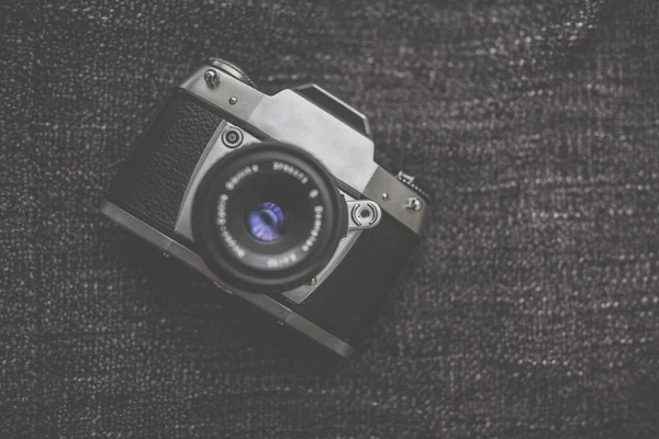 Old retro camera on vintage wooden boards abstract background with lens, close-up photo of old camera lens, image is retro filtered, selective focus