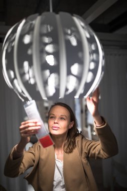 Güzel, genç bir kadın modern bir ev mobilyası mağazasında dairesi için doğru mobilyayı seçiyor (renk tonlu görüntü; sığ DOF)