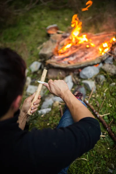 Jongeman Maakt Gereedschap Van Hout Bij Een Kampvuur — Stockfoto